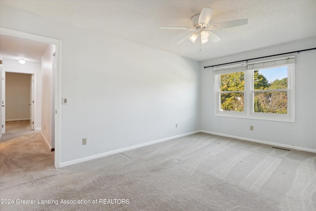 spare room with ceiling fan, light colored carpet, and a textured ceiling