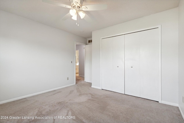 unfurnished bedroom with light carpet, ceiling fan, and a closet