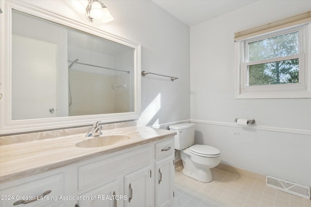 bathroom with tile patterned flooring, vanity, walk in shower, and toilet