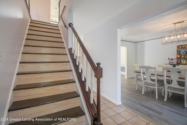 stairs featuring hardwood / wood-style flooring and an inviting chandelier