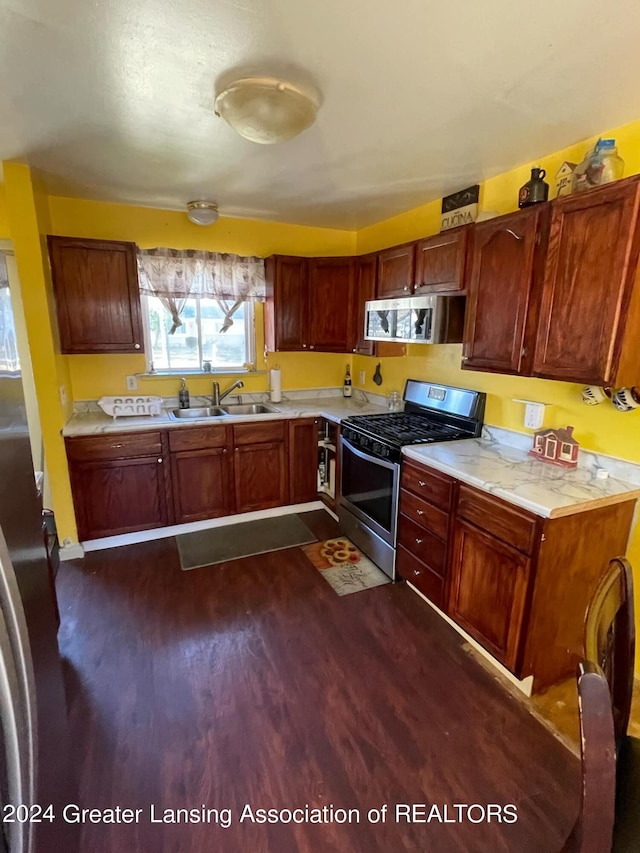 kitchen with appliances with stainless steel finishes, dark wood-type flooring, and sink