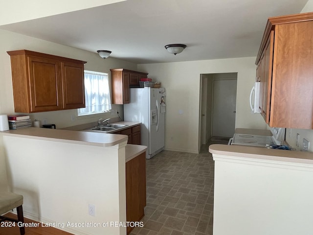 kitchen with kitchen peninsula, white appliances, sink, and a kitchen breakfast bar