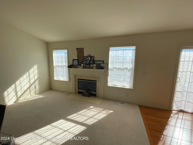 unfurnished living room featuring light wood-type flooring and a healthy amount of sunlight