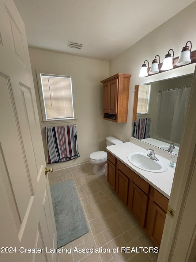 bathroom with vanity, toilet, and a wealth of natural light