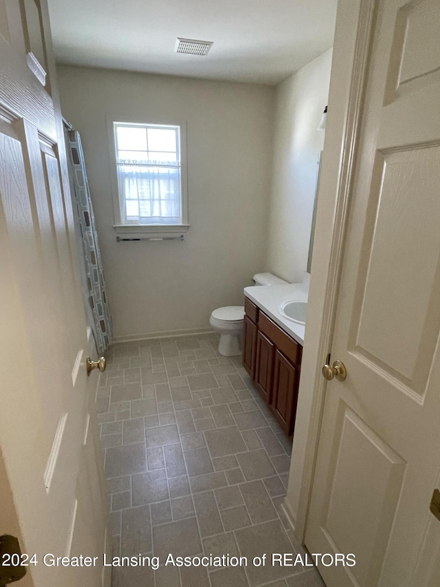 bathroom featuring toilet, vanity, and a shower with curtain