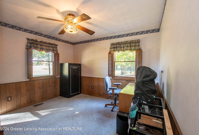 carpeted office with wood walls and ceiling fan