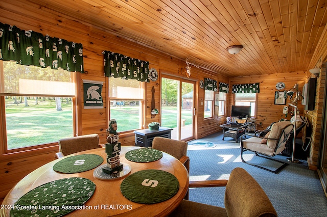 carpeted dining area with wooden ceiling and wooden walls