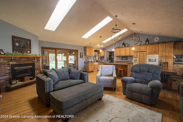 living room featuring lofted ceiling with skylight, a fireplace, and light hardwood / wood-style floors