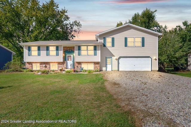 bi-level home featuring a garage and a lawn