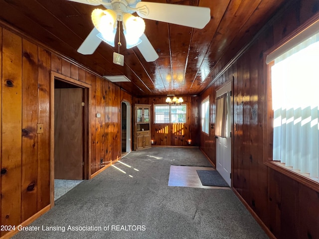 interior space featuring carpet floors, wood ceiling, wooden walls, and ceiling fan