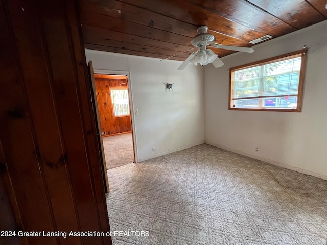 carpeted spare room with ceiling fan and wooden ceiling