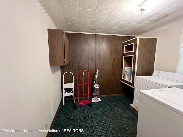 laundry area with wood walls, crown molding, and washer and clothes dryer