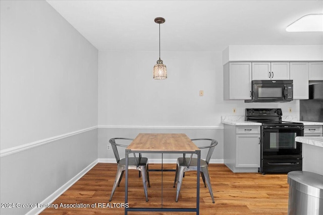 kitchen with decorative light fixtures, black appliances, and light wood-type flooring