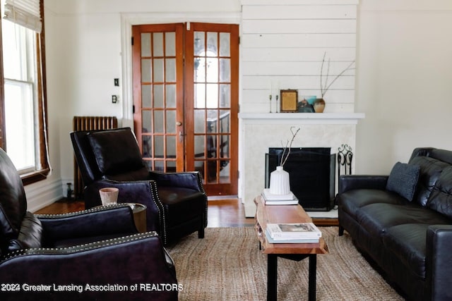 living room with wood-type flooring, a premium fireplace, and french doors