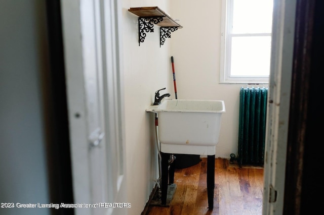 laundry room featuring hardwood / wood-style floors and radiator