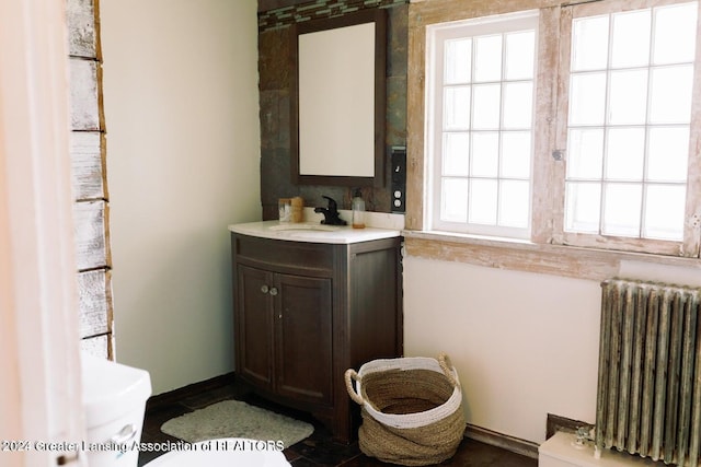 bathroom featuring a wealth of natural light, toilet, vanity, and radiator