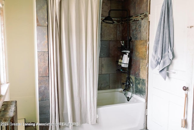 bathroom featuring radiator and shower / tub combo with curtain