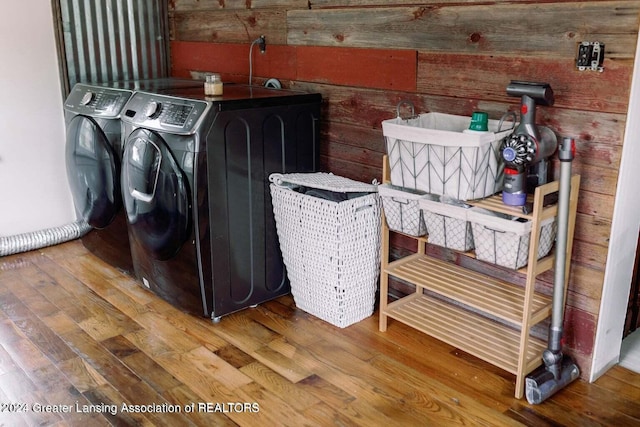 laundry area featuring independent washer and dryer, hardwood / wood-style flooring, and wooden walls