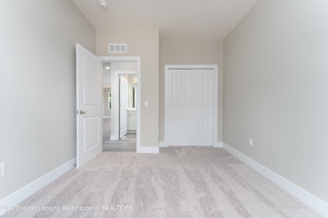 unfurnished bedroom with baseboards, a closet, visible vents, and light colored carpet