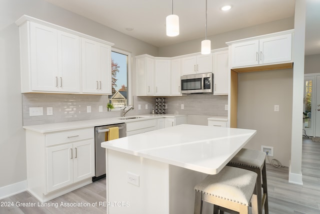 kitchen featuring appliances with stainless steel finishes, light countertops, a kitchen island, and white cabinetry