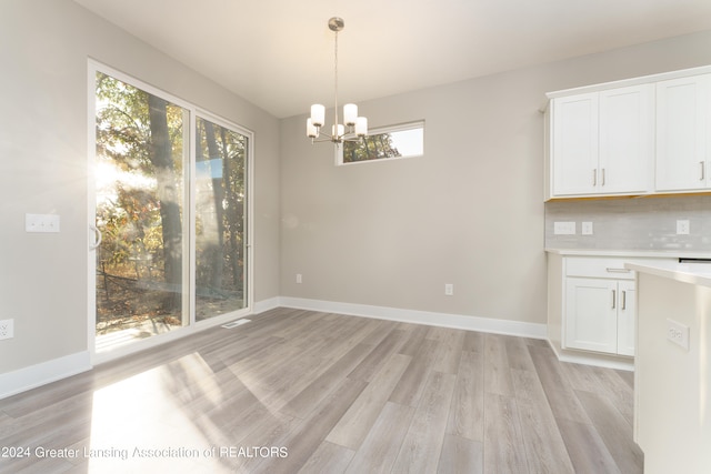 1534 Lytell Johnes Path # 76, Williamston, MI 48895 - unfurnished dining area featuring light wood-style floors, a chandelier, and baseboards