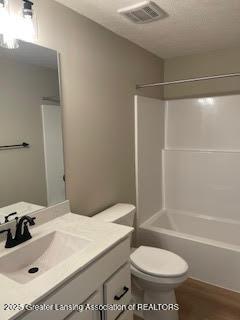 full bath with visible vents, vanity, toilet, and tub / shower combination