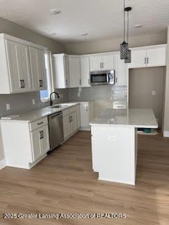 kitchen with a center island, decorative light fixtures, light countertops, appliances with stainless steel finishes, and white cabinetry