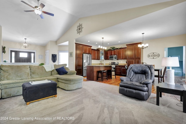 carpeted living room with ceiling fan with notable chandelier and vaulted ceiling