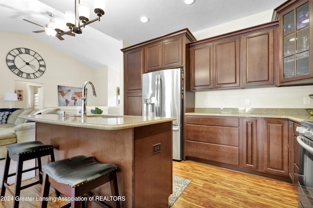 kitchen with a breakfast bar, sink, light hardwood / wood-style floors, vaulted ceiling, and appliances with stainless steel finishes