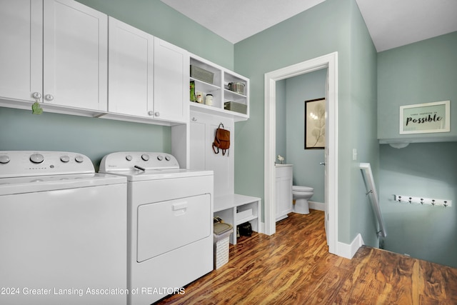 laundry room with dark wood-type flooring, washing machine and dryer, and cabinets