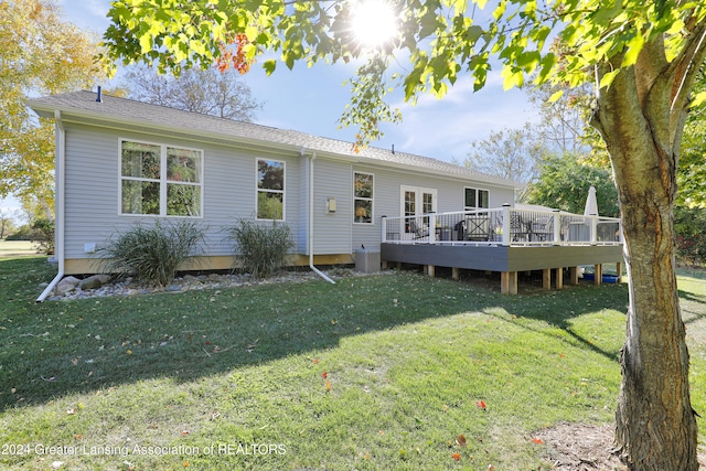 rear view of property with a wooden deck and a lawn