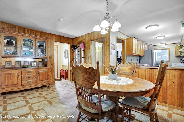 dining space featuring a notable chandelier and wood walls