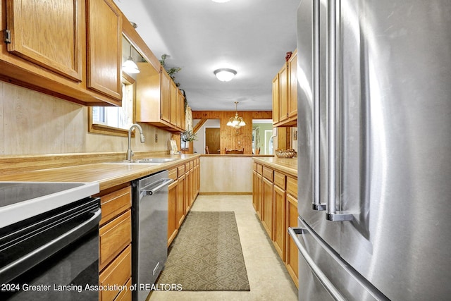 kitchen with pendant lighting, a notable chandelier, stainless steel appliances, and sink