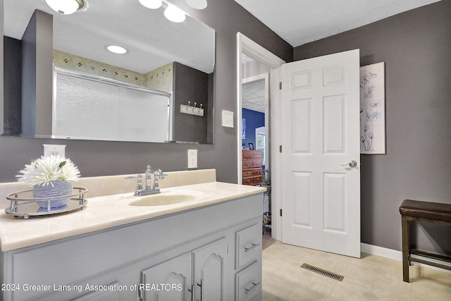 bathroom with vanity, a shower with shower door, and tile patterned floors