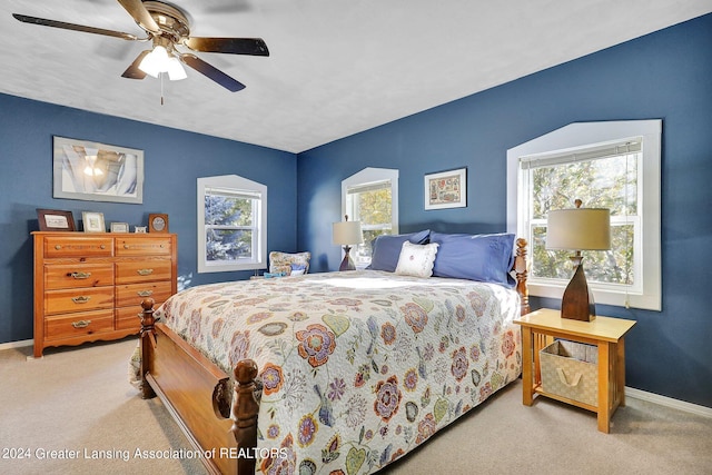 bedroom featuring ceiling fan, light carpet, and multiple windows