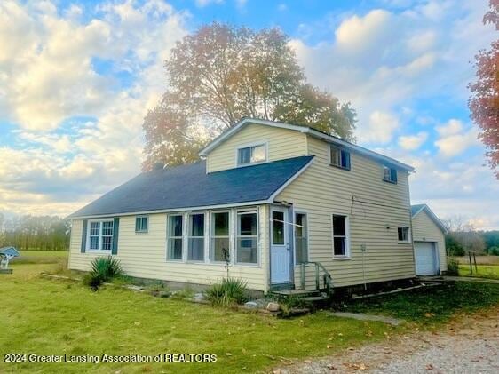 rear view of property with a garage and a yard