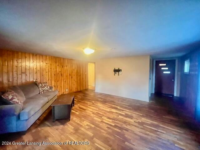 unfurnished living room featuring wooden walls and wood-type flooring