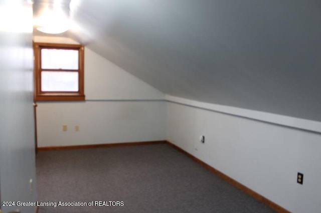 bonus room with lofted ceiling and light colored carpet