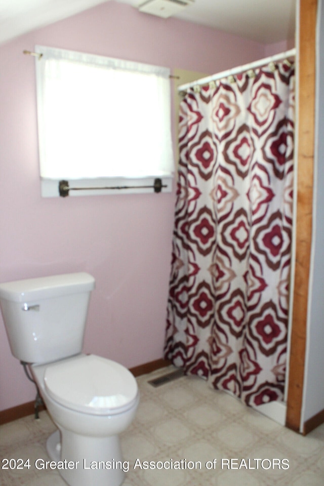 bathroom with lofted ceiling, walk in shower, and toilet