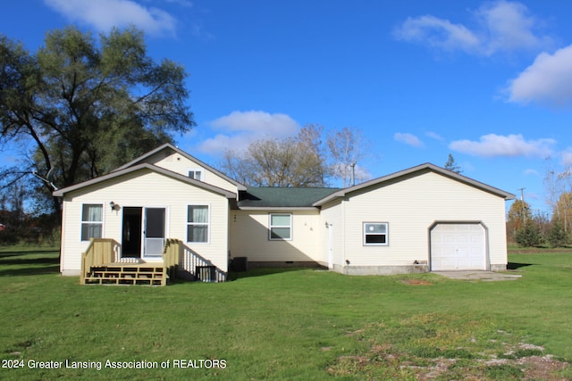 rear view of property with a garage and a lawn