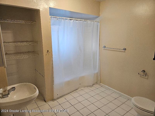 full bathroom featuring sink, shower / bath combo with shower curtain, toilet, and tile patterned floors