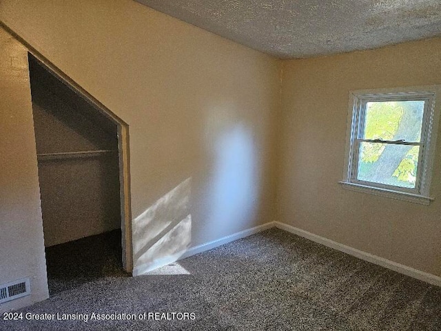 carpeted empty room with a textured ceiling