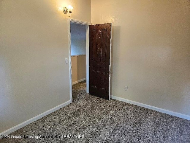 unfurnished room featuring dark carpet