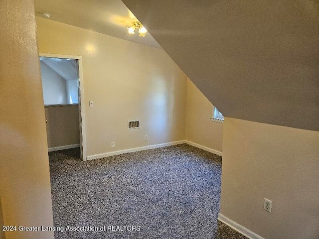 bonus room with dark carpet and vaulted ceiling