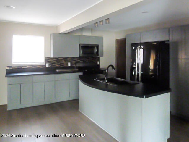 kitchen featuring decorative backsplash, black refrigerator, gray cabinetry, and light hardwood / wood-style floors