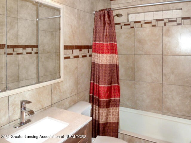 full bathroom with toilet, backsplash, tile walls, vanity, and shower / bathtub combination with curtain