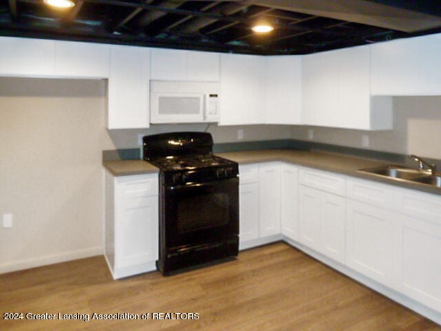 kitchen with black range with electric stovetop, sink, white cabinets, and light hardwood / wood-style floors