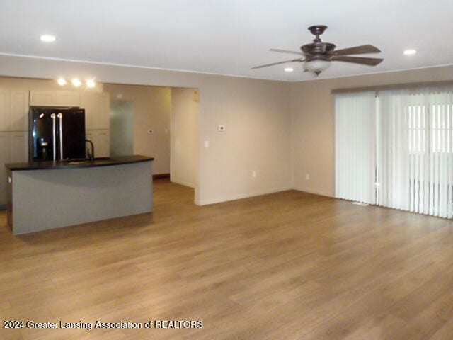 unfurnished living room featuring light hardwood / wood-style floors, sink, and ceiling fan