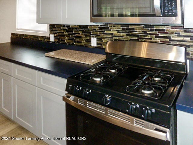 kitchen with backsplash, appliances with stainless steel finishes, and white cabinetry