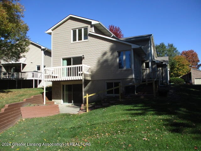 rear view of house featuring a lawn and a deck